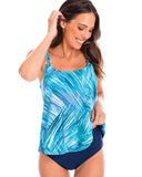 A woman wearing a blue geometric patterned tankini top with a scoop neckline, accompanied by a navy full brief.