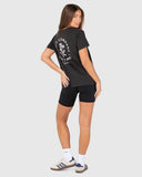 Woman wearing a black t-shirt with a logo and black shorts on a white background Unit Ladies Tees - Blush - Washed Black