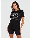 A woman wearing a black crew neck t-shirt with text print in the center that reads 'UNIT CO 1982 SEE NO LIMITS'.