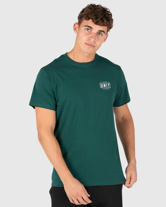 A man wearing a dark green crewneck t-shirt with a small white 'UNITY' logo on the left chest, photographed against a light gray studio background. Unit Mens Tees - Index - Forest Green