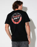 A man wearing a black t-shirt from the back, showing a large circular graphic print on the back in red, white, and orange. The graphic features the text 'UNIT' and 'SEEN NO LIMITS'.