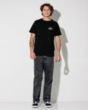 A man modeling a black short-sleeve t-shirt with a small white and red 'UNITY' logo on the left chest, paired with faded dark gray jeans and black-and-white sneakers, standing against a white studio background.