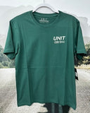 Green t-shirt with 'UNIT' logo on a hanger against a blurred outdoor background