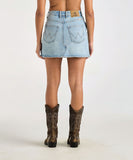 Person wearing a light blue denim skirt and cowboy boots on a white background Wrangler Repair Mini Skirt - Blue Tour