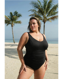 Woman in a black swimsuit standing on a beach with palm trees in the background