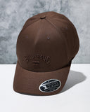 Text: Billabong Arch Flexfit 110 Snapback Cap in Coffee Bean front view showcasing the rich brown colourway structured five-panel crown curved Permacurv visor and classic surf-inspired cap silhouette, sold by Point Break Cambridge local family surf shop at 63 Duke Street.