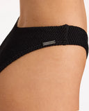 Billabong Womens Summer Hi Hike Pant Bikini Bottom in Black Sands charcoal black close up view highlighting the premium soft ribbed texture fabric weave pattern, seamless edge lining, and metal brand logo badge detail, sold by Point Break Cambridge local family surf shop at 63 Duke street.