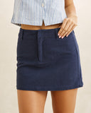 A navy blue mini skirt worn by a model, paired with a blue and white striped cropped top, against a plain beige background. Rhythm Canyon Mini Skirt