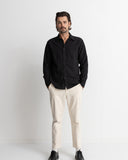 A man modeling a black long-sleeve button-down shirt and off-white trousers against a plain white studio background. Rhythm Men's Classic Linen LS Shirt – Vintage Black