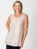 Woman wearing a sleeveless, light-colored top against a plain background