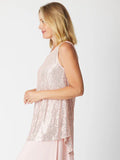 Woman wearing a sparkly pink sleeveless top against a white background