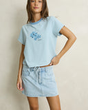 Model wearing the Rhythm Daisy Floral Stripe Tee - Baby Blue on a plain background