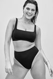 Woman wearing a black bikini against a plain background