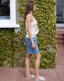 Side profile of the Honey Denim Belle Denim Jort in Blue J85 detailing the longline knee-length fit and outseam stitching.