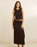 A woman modeling a dark brown sleeveless crop top and matching drawstring midi skirt against a warm beige studio background. Rhythm Indie High Neck Tank - Chocolate