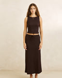 A woman modeling a dark brown ribbed knit two-piece set consisting of a sleeveless crop top and a matching drawstring maxi skirt, set against a warm beige textured studio backdrop. Rhythm Indie Maxi Skirt - Chocolate