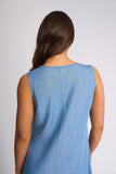 A woman viewed from the back wearing a sleeveless light blue denim-style top against a plain light gray studio background.