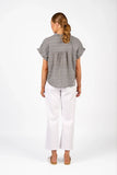 Back view of the Knewe Label Addison Top in Ink Gingham navy and white check, showcasing the elegant neckline and relaxed fit layout. Woman wearing a gray patterned blouse and white pants on a white background