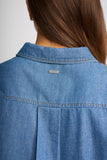 Close-up back view of a person wearing a blue denim shirt, showing the collar, stitching, and a small KLEINE brand label.