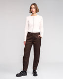 Woman wearing a white blouse and brown pants on a gray background