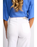 White high-waisted jeans with a small beige brand tab on the back waistband, worn by a model in a blue blouse against a light gray background. Detailed close-up macro view of the premium stretch white denim fabric texture, hardware, and stitching on the Knewe Label jeans.