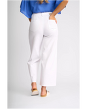 Back view of the Knewe Label Index Jean in White Denim, displaying the classic pocket design and sculpting fit. White cropped wide-leg pants shown on a model from the back, paired with a blue blouse and beige slide sandals, against a light gray studio background.