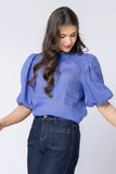 Woman wearing a blue blouse with puffed sleeves against a white background