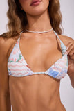 A close-up of a woman wearing a triangle bikini top with a pastel multicolor print featuring pink, blue, and green floral and wavy patterns on a white base.