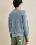 A person shown from the back wearing a light blue knit crewneck sweater and olive green pants against a neutral beige backdrop. Rhythm Mens Polu Crew Knit - Washed Blue