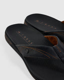 Reef Phantom Lux Jandal in Black flip flop sandals close up view highlighting the textured leather strap stitching, debossed brand icon, and soft lining, sold by Point Break Cambridge local family surf shop at 63 Duke street.