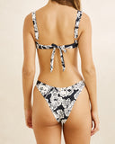 Black and white floral bikini on a beige background. Back view of the Rhythm Georgia Floral Hi Cut Pant in Cream highlighting the cheeky seat coverage and clean waistline.
