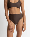 Rhythm Classic Hi Waste Pant in Chocolate brown bikini swimsuit bottoms close up view highlighting the premium smooth swim fabric weave quality seam detailing and subtle logo details, sold by Point Break Cambridge local family surf shop at 63 Duke street.