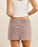 Rhythm London Check Bias Cut Mini Skirt in Chocolate brown back view showing the clean tailored fall and smooth continuous fabric check drape, sold by Point Break Cambridge local family surf shop at 63 Duke street.