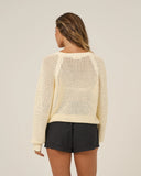 Woman wearing a beige open-knit sweater and black shorts on a plain background Back view of the Salty Crew Women's Surge Sweater in Off White, displaying the relaxed fit back panel and raglan sleeve knit construction.