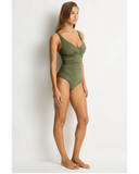 A woman modeling a one-piece swimsuit in olive green, standing in profile against a plain white studio background. Side profile angle of the Khaki Sea Level Essentials Cross One Piece, highlighting the smooth side seams and supportive fit.