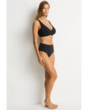 A woman modeling a black two-piece bikini set against a plain white studio background. Side profile angle of the Black Sea Level Essentials Retro High Waist Pant, highlighting the comfortable high-rise fit and clean side seams.