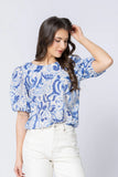 Woman wearing a blue and white patterned blouse against a plain background