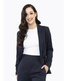 A woman smiling, wearing a navy longline blazer with a peak lapel and double-breasted button closure, paired with a white top and navy pants.