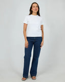 Woman wearing a white t-shirt and blue jeans on a plain background