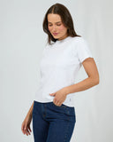 Woman wearing a white t-shirt and blue jeans against a plain background