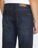 Back view of the Volcom Solver Modern Fit Denim Jeans in Vintage Blue wash showcasing the signature asymmetric yoke and stone embroidery on the pocket.