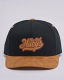 The Mad Hueys Ball Twill Snapback in Black front view showing the structured crown flat brim and custom embroidered brand graphic, sold by Point Break Cambridge local family surf shop at 63 Duke street.