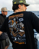The Mad Hueys Plank Captain Cooked SS Tee in Black close up view highlighting the premium soft cotton knit fabric weave texture and high density screen print graphic finish detail, sold by Point Break Cambridge local family surf shop at 63 Duke street.
