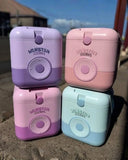 Four Vanstar coolers in purple, pink, and blue stacked on a sandy surface.