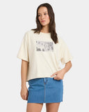Woman wearing a cream t-shirt with a graphic design and a blue denim skirt on a white background