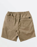 Beige shorts with a brand label on a light gray background. Back view of the Volcom Boys Youth Frickin Elastic 15 inch Shorts in Khaki highlighting the rear welt pockets and signature asymmetric yoke line.