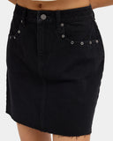 Volcom Womens Stoneray Skirt in Black close up view highlighting the premium 100% cotton fabric texture quality stitching metal shank button front pocket eyelet detailing and signature embroidered Volcom Stone logo, sold by Point Break Cambridge local family surf shop at 63 Duke Street.