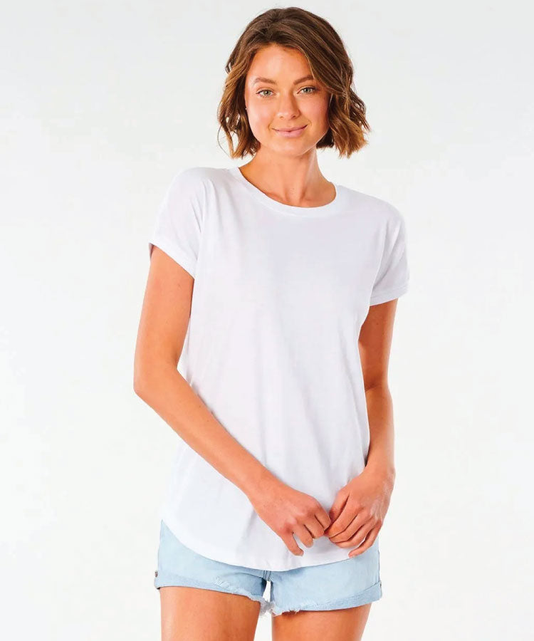A female model wearing a white t-shirt and blue denim shorts. Rip Curl Plains Tee - White