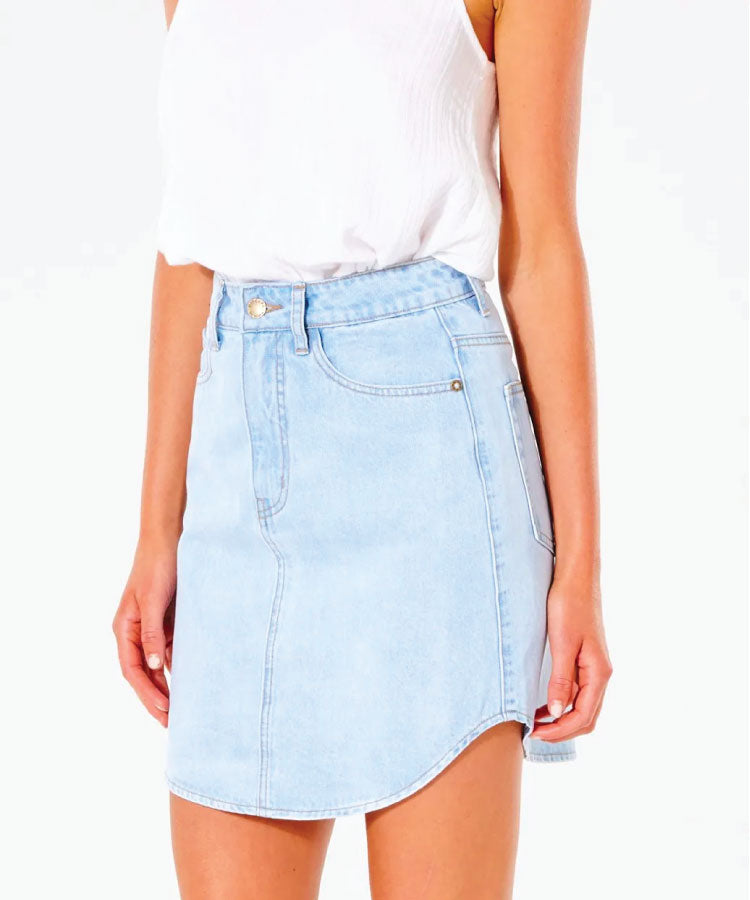 A light blue denim skirt with a A-line shape, scoop hem, and back pockets, worn with a white top.