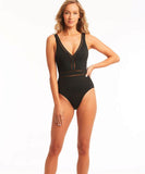 A female model wearing a solid black one-piece swimsuit with a spliced waisted design.